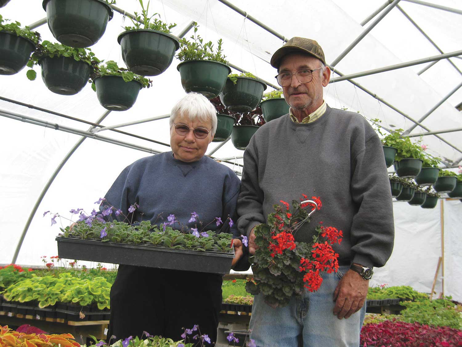 Mertyann and Art Boe in a greenhouse, holding plants