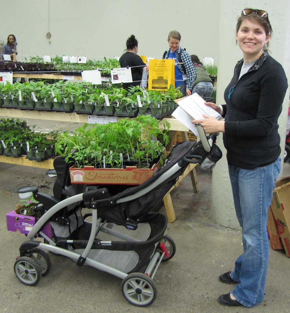 Woman with a flat of plants sitting on a baby stroller