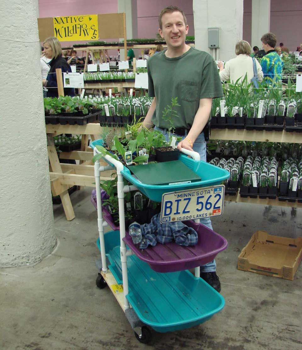 Three shelves made out of plastic sleds, connected white PVC pipes, with casters