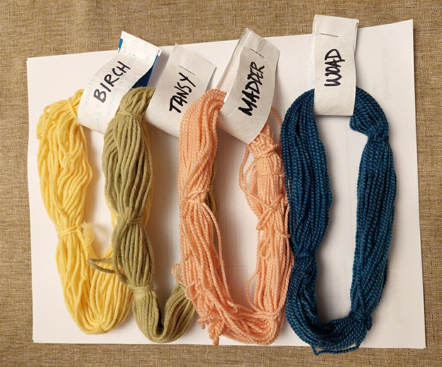 4 yarn skeins dyed in yellow, green, peach, and dark blue