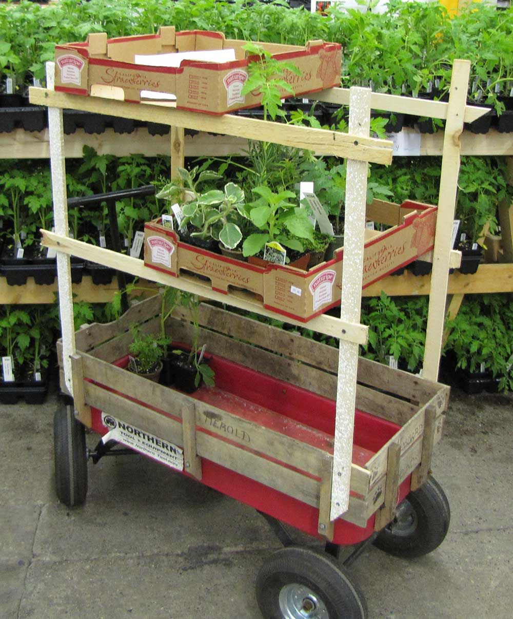 Little red metal wagon with rough wood structure built above to hold boxes