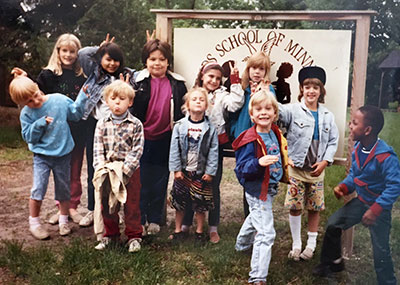 Children gathered in front of an early Friends School of Minnesota sign