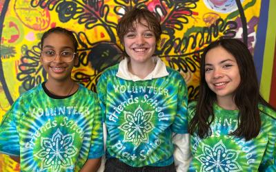 Three middle-school-age students in green-blue tie dye shirts that say Friends School Plant Sale