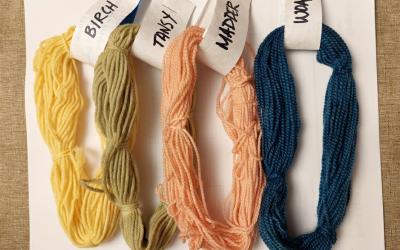Four yarn skeins dyed in yellow, green, peach and dark blue