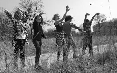 Five middle school students throwing something in a grassland