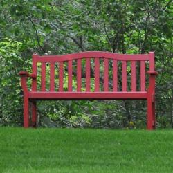 A red bench in a green garden setting